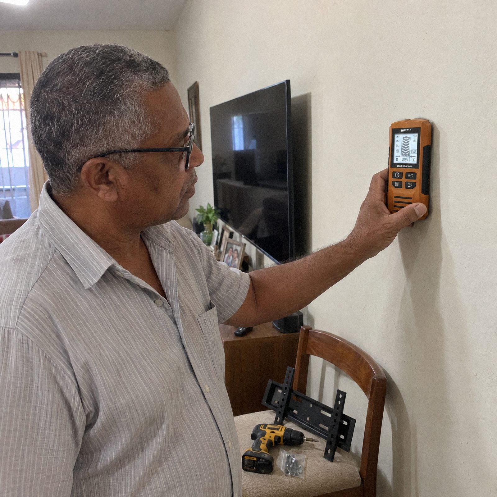Homem passando o Detector de Parede Carbon antes de instalar a TV